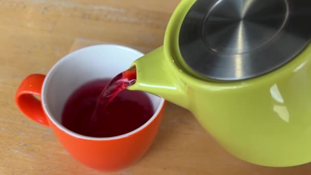 Выливать Чай Гибискуса Зеленого Чайника Красную Оранжевую Чашку Деревянном Столе — стоковое видео