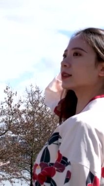 Gezgin kız güzel doğulu kız başını sallayarak yürür kiraz çiçeklerinin arka planında saçlarını uzatır Kanadalı Vancouver demir bir köprüde sakura yapar 