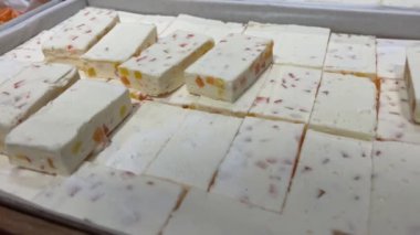 Mağazanın vitrininde jöle parçaları olan marşmelovlar self-servis beyaz tatlı parçaları toplar ahşap bir tahtadan fındık satın alır. Yüksek kalite 4k görüntü