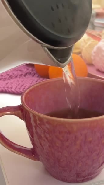 Kokend Water Een Roze Beker Gieten Achtergrond Van Mandarijnse Marshmallows — Stockvideo