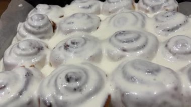 Fırında tarçınlı çörek. Tarçınlı çörek veya tarçınlı çörek üretimi. Pişmiş çörekler Tarçınlı çörekler pişiyor ve yükseliyor. Tarçınlı ekmeklere krema dök. Taze pişmiş ev yapımı.