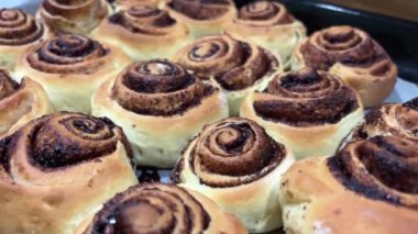 Fırında tarçınlı çörek. Tarçınlı çörek veya tarçınlı çörek üretimi. Pişmiş çörekler Tarçınlı çörekler pişiyor ve yükseliyor. Tarçınlı ekmeklere krema dök. Taze pişmiş ev yapımı.