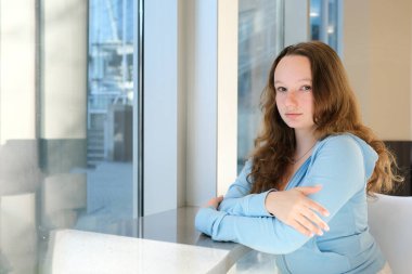 New York panoramik manzaralı güzel gülümseyen bir çalışan ofiste duruyor. Modern işyeri kavramı. Yüksek kalite fotoğraf