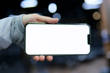 Spor salonunda elinde beyaz bir ekranla uzun kollu gri giysilerle Great Mobile Offer 'ın reklamını yapan bir telefon. Yeni Uygulamaya Duygusal Tepki Veren Kadın Akıllı Telefon 'u Gösteriyor