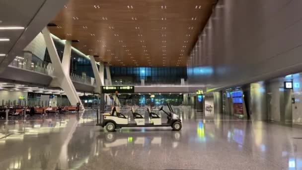 ハマド国際空港 ドーハ カタールの出発ホールは 夜にカタールの免税を表示し 乗客が空港の途中で歩く手荷物をドラッグしました ドーハ空港 2024 — ストック動画
