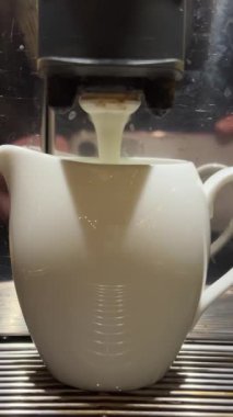 Bir fincan kahve yapmak için bir bardak espressoya süt dökmek, dipsiz iskele filtresi ile 4K kahve makinesi. Espresso bardağa damlıyor. Yüksek kalite 4k görüntü