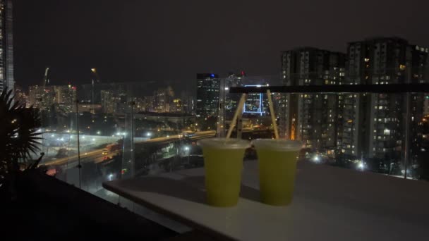 在夜市的背景下 在酒店的屋顶上 人们正在用塑料杯子里的冰块喝着甘蔗饮料 玻璃杯放在桌子上 不放甘蔗饮料 — 图库视频影像