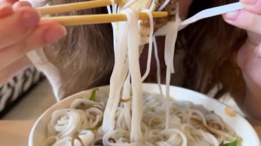 Genç bir kız Vietnam 'daki alışveriş merkezinde tavuk ile nefis pho bo çorbası içiyor. Ho Chi Minh City' de ucuz yemekler pişiriyor. Saygon