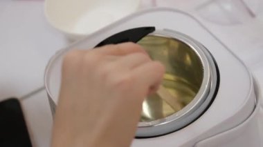 Kadın evde mum yapıyor, kadın ellerini kapatıyor tavadan silikon kalıba sarı sıvı balmumu döküyor. Yüksek kalitede kesilmiş vetil mum aromalı mum yapar.