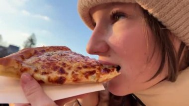 Kış kızındaki sokak yemekleri, Romanya 'da Bükreş' e yakın bir yerde çekilmiş bir şapkayla sokak kızının üzerinde pizza yiyor. Öğle yemeği