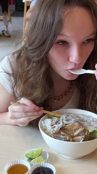 在胡志明市的购物中心里 一个年轻姑娘和鸡肉一起吃着美味的凤尾鱼汤 吃着便宜的 健康的传统越南汤 西贡人 — 图库视频影像