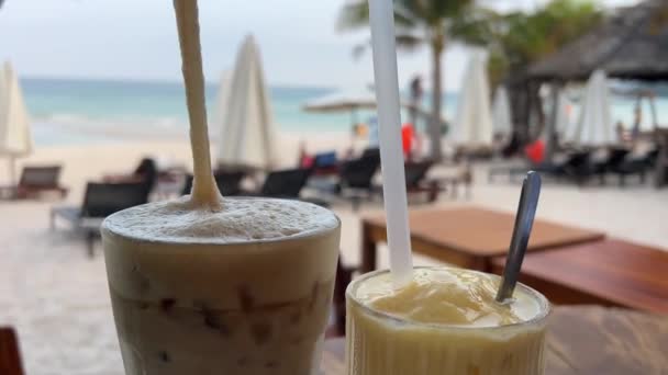 夏の海辺でマンゴーのスムージーおいしいアイスラテコーヒー 屋外のビーチカフェで冷たい飲み物 バリ島を旅して楽しむ 高品質の4K映像 — ストック動画