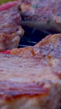 Genç, beyaz bir adam evinin arka bahçesinde dikilirken ızgarada ızgara biftekli sıcak biber ile sıcak ve sulu biberi ters çevirir. Yüksek kalite