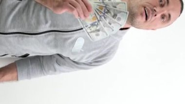 Gri eşofmanlı zengin bir adam bir tomar para sallıyor. Kazanılan para nefes alır. 