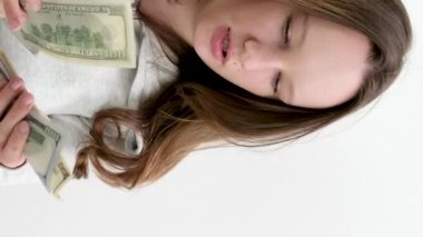 Sakin yüzlü genç bir kadın beyaz arka planda 100 dolarlık banknotlar sayıyor güzel bakımlı saçlar güzellik salonu için para ödüyor. Eski ve yeni banknotlar