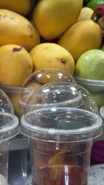 Yerel gece pazarında çeşitli taze meyve çeşitlerinin plastik bardaklarda yakın çekimleri. Tayland, Pattaya. Meyve Suyu Gece Pazarı