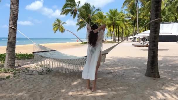 海滩上优雅的女人穿着比基尼 戴着太阳镜 享受夏天的旅行 很时髦的女士戴着太阳帽 热带海滨的年轻貌美女子在风中起舞 — 图库视频影像