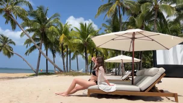 선글라스를 비키니에서 여행을 즐기는 해변에 우아한 모자를 해변에 바람에 — 비디오