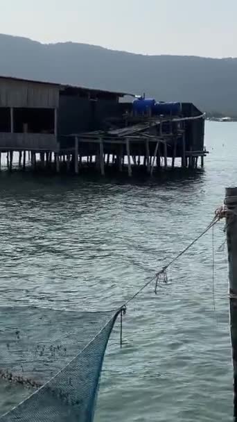 印度洋捕鱼船上的渔民们在越南的养鱼场捕到了鱼 在水面上的餐馆捕鱼网木房子无云的天空和平静的水 — 图库视频影像
