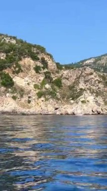 Korfu adası yakınlarındaki tekne turu temiz su dağlarının derinliklerinde doğal bahar mevsiminde kayıkçıları geçiyor. turistler ve gezginler