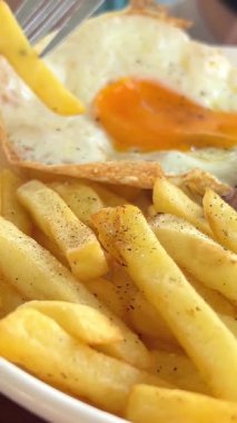Etli patates ve kızarmış yumurta kahvaltısı, çatalla yakın çekim ile yenir.