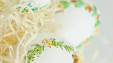 Kamera yavaşça zumlarken üç büyük kaz devekuşu hindi yumurtası vuruyor. Yumurta kabuğunda kurdele nakışlı, el yapımı talaşla Paskalya için yumurta işliyor.