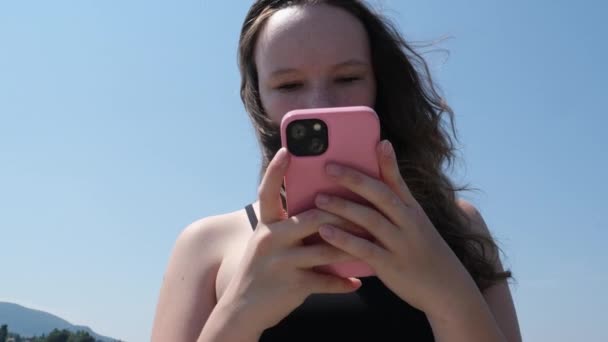 海でスマートフォンでセルフィーを取る若い女の子 — ストック動画