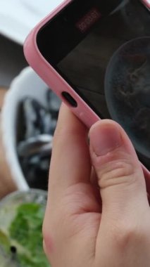Kız cep telefonuyla deniz ürünleri tabağında tatlı ve ekşi soslu kremalı midye fotoğrafları çekiyor. Mojito. 