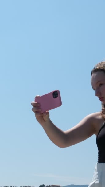 若い女の子は電話を使用し 空に向かって飛行機の背景に写真を撮ります — ストック動画