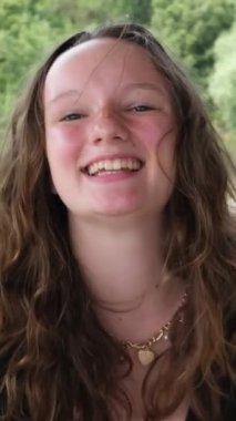 Nehrin yeşil rengi. Siyah elbiseli genç bir kız su ve yeşil ağaçlı kayalık kıyılara karşı poz veriyor.