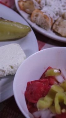 Makedonya 'daki bir restoranda, yemek kırmızı kare masa örtüsü üzerinde servis ediliyor. Izgara kabak, ızgara biber, domatesli salata peynirli çörek.