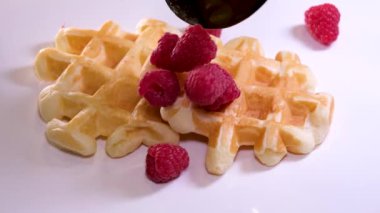 Dilimlenmiş çilekler waffle 'ın üstüne düşer. Kremalı ve ahududulu Viyana Waffle 'ı pişirdim.