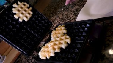 Viyana Belçika waffleları kıvrılmış. Elektrikli waffle ızgarasında pişirme işlemi. Yemek pişirmek. Yüksek kalite 4k görüntü