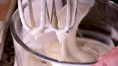 4K Mutfak Karıştırıcısı kremalı hamur çırpıcısını hızla çeviriyor. Mutfak makinesi çalışıyor. Yemek işleyicisi yumurtanın beyaz yumurtalarını kalın bir köpüğe çevirdi. Yüksek kalite 4k görüntü