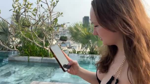 프리랜서는 수영장 근처의 의자에 노트북에서 작동합니다 소녀는 휴가에 작업을 노트북을 — 비디오