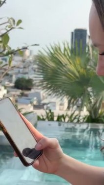Serbest çalışan bir kadın havuz kenarında iskemlede oturuyor ve dizüstü bilgisayarla çalışıyor. Kız tatilde uzaktan kontrol için dizüstü bilgisayar kullanıyor ve e-posta ile iyi haberler alıyor. Yüksek kalite 4k görüntü