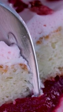 Flamingo pastası ve çilek. Makro ve kaydırak atışı, Halation etkisi restoran masasında yakın plan tatlı, kek ya da dutlu cheesecake. Kız kaşığı elinde tutuyor, kırıyor ve tadıyor.