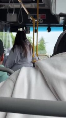 Otobüsteki gerçek insanlar evlerine giderken yarı yarıya boş araçla tanınmayan beyaz kazaklı bir kız boş bir koltuğa oturmuş elinde bir çanta ve telefonla BC, Vancouver, Kanada, 07.07.2023