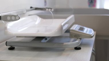 Deneyimli bir çocuk doktoru hastanedeki bebek kilolarını tartıyor. Bebek pulları