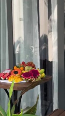 Taze meyve tabağı ve yazlık şık plaj aksesuarları, tropik plaj yaşam tarzı. Tabak. Otel verandasında meyve var. 