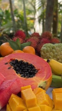 Tahtaya yerleştirilmiş taze meyve, masada, üzümler, portakallar, şeftaliler, muzlar, ananas, karpuz ve diğerleri, kepçeleyip indirirken..