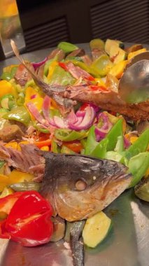 Suşi büfesinden lezzetli yiyeceklerle dolu beyaz bir tabak. Somon nigiri ve maki rulo. Bir el maki dürümlerinden birini yemek çubuğuyla alıyor. Suşi büfesi, Gıda Konsepti
