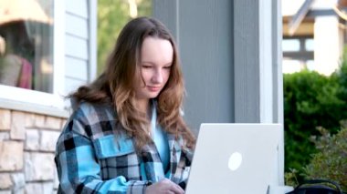 Genç ve mutlu bir kadın laptopunu sokakta bankta otururken kullanıyor. Yüksek kalite 4k görüntü