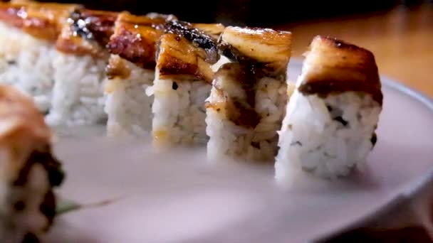 乾いた氷の装飾が施されたプレートの上のおいしいレストランアジア料理寿司ウナギのマグロのセットを提供しています白い煙が宇宙テキスト広告の周りに包まれて流れる石板上のおいしい寿司 — ストック動画