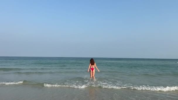红色泳衣 年轻迷人的金发美女 戴着太阳镜 留着蓬松的头发 摆出姿势 在海滨的热带海滩上自拍 在海浪中拿着智能手机的快乐女人 — 图库视频影像