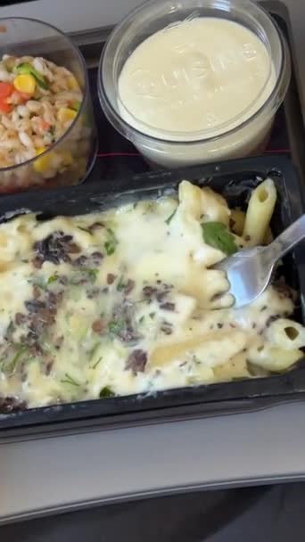 飛行機でパスタを食べる エコノミークラスのための軽食サービストレイ パスタ 調味料のフルーツ サラダ キュウリ ジュースとバターのグラス 選択的な焦点 — ストック動画