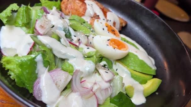 レタスの葉とトマトがボウルに落ちる新鮮なサラダは 白いテーブルに健康的な食材を提供し ゆっくりとした動きをしました 卵とアボカドとチーズとサラダ — ストック動画