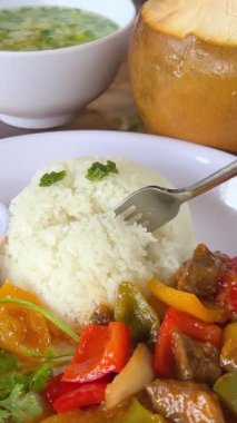İnsan eli doğayla esmer pirinç yemek için kaşık kullanır. Tatlı ve ekşi soslu beyaz pirinç ve sebze arka planda çatalla yenir. Hindistan cevizi ve çorba.