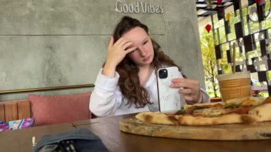 Aşçı kız fırından çıkan sıcak pizzayla selfie çekiyor. Video günlüğünü parlak mutfakta kabul et.