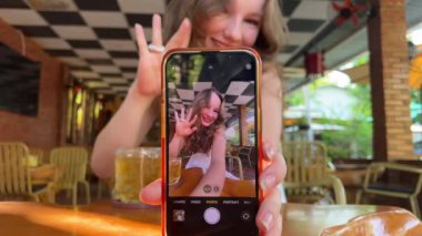 Mobil web kamerası görüntüsü gülümseyen çekici İspanyol kadın el sallıyor, sosyal ağlarda hikayeleri çevrimiçi yayınlıyor, selfie videosu kaydediyor, uzaktan konuşmaya başlıyor. Kız telefonu